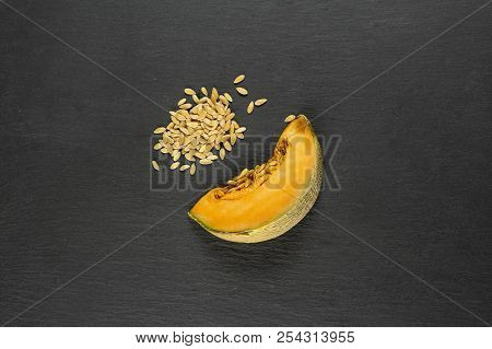 One Slice Of Fresh Melon Cantaloupe Variety With Seeds Around Flatlay On Grey Stone