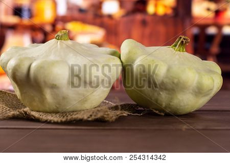 Group Of Two Whole Summer White Pattypan Squash On Linen Cloth With Rustic Wood Kitchen In Backgroun