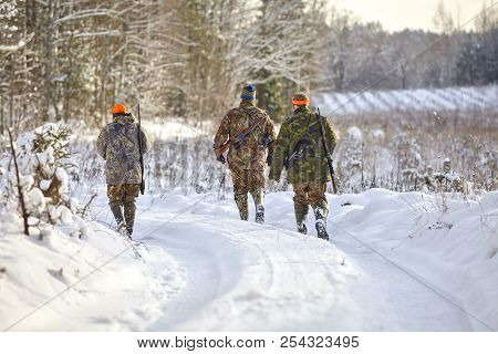 Group Of Hunters In Winter Forest With Carbines And Shotgun