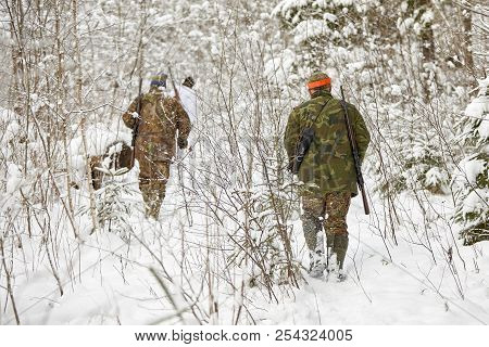 Group Of Hunters In Winter Forest With Carbines And Shotgun