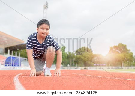 Fit And Confident Fat Boy In Starting Position Ready For Running. Kid Athlete About To Start A Sprin