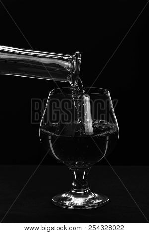 Brandy Or Cognac Filling Glass From Bottle. Beverage For Luxury Occasions. Whiskey Poured Into Low G