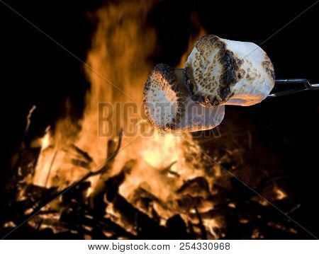 Two Marshmallows Being Roasted Over A Campfire To Make Smores