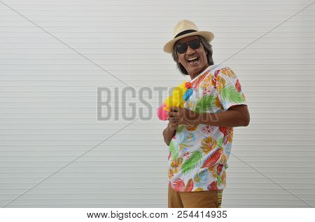 Happy Elderly Traveler Asian Man Wearing Summer T-shirt, Straw Hat And Sunglasses Holding Colorful W
