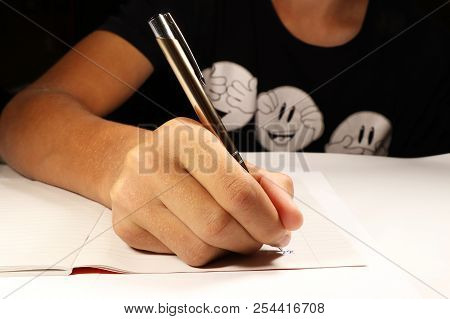 A Young Boy With Black T-shirt Writing Dictation In English Lesson. Elementary School. Steel Pen