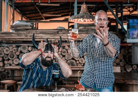 Two Mature Men Entertaining Theirselves Watching Football In Pub