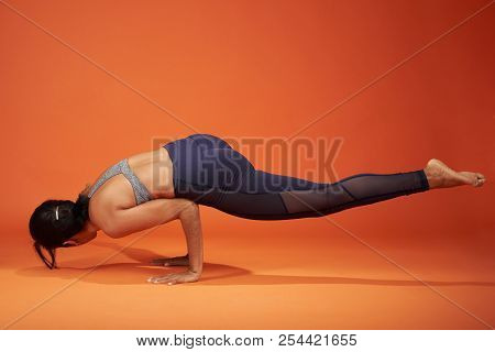 Yoga Pose Dedicated To The Sage Koundinya Showing Girl On Orange Color Studio Background