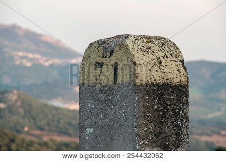 Ancient Painted Stone Road Marker For D81 In The Balagne Region Of Corsica With Hills And Villages I