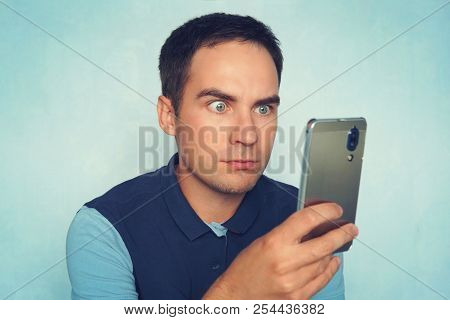 Shocked And Surprised Asian Man Looking Smartphone. Amazed Young Guy Reads A Message On The Phone.
