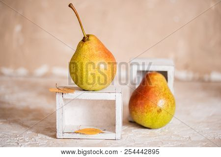 Autumn Pear In A White Old Wooden Small Box. Life Style. Yellow Autumn Leaves On A Concrete Light Ba