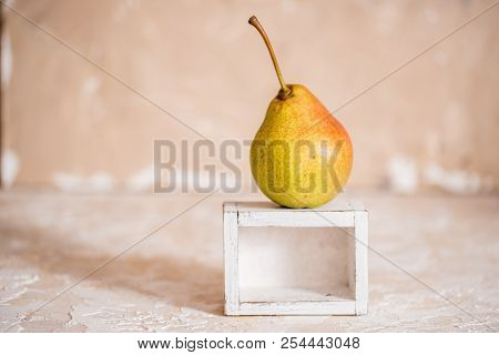 Autumn Pear In A White Old Wooden Small Box. Life Style. Yellow Autumn Leaves On A Concrete Light Ba