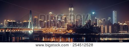 Chongqing skyline with urban buildings, bridge and Hongyadong shopping complex at night.