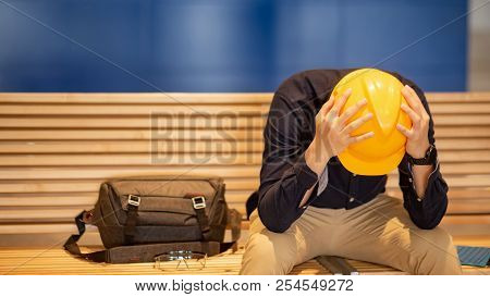 Young Asian Engineer Or Architect Man Feeling Tried And Worried While Sitting On Bench Holding His P