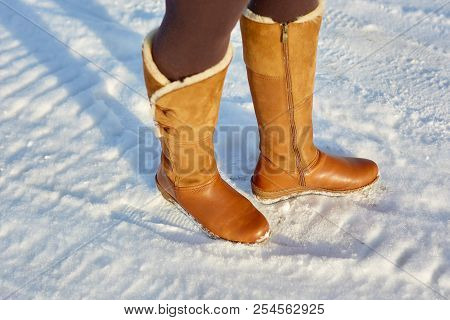 Leg Woman Winter Brown Fur Boots Walking On The Snow In A Winter Park. Closeup Outsole Of Warm Boot.