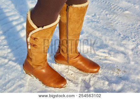 Leg Woman Winter Brown Fur Boots Walking On The Snow In A Winter Park. Closeup Outsole Of Warm Boot.