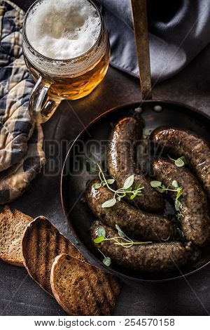 Roasted Sausages In Pan With Bread Herbs And Draft Beer.
