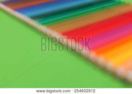 Blurred Photo Of A Row Of Various Bright Multicolored Felt Pens Lying Diagonally On A Green Surface.