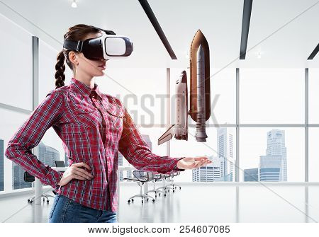 Young Caucasian Woman In Modern Office Interior Trying Virtual Reality Helmet And Viewing Space Shut