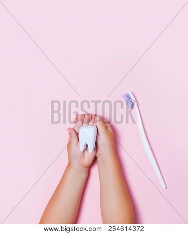Child's Hands Holding Big Tooth And Toothbrush