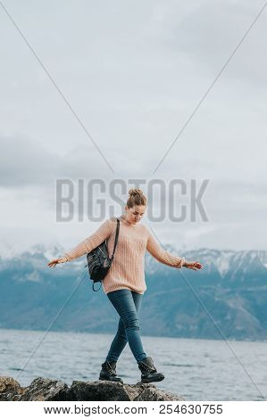 Outdoor Portrait Of Young Woman Resting By The Lake On A Fresh Cold Day, Wearing Warm Pullover And B