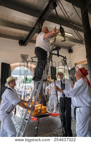  Alkmaar, Netherlands - July 20, 2018: Group of cheese carriers fixing the cheese scale in the Waag building 