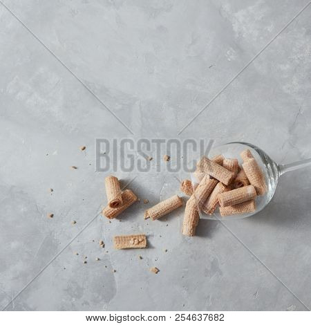 A glass of tasty wafer cripsy rolls on a gray concrete table with place for text. Top view