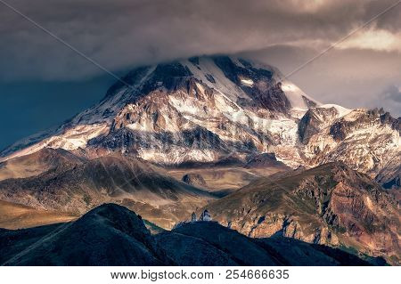Dramatic Landscape View Of Mt Kazbeg And Tsminda Sameba Church, Caucasus Mountains, Country Of Georg