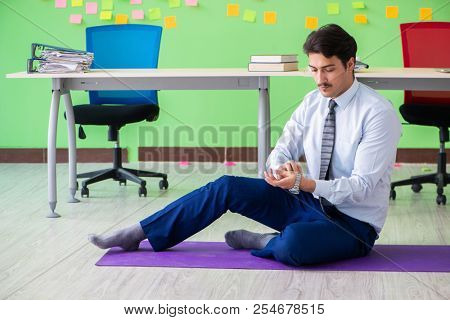 Man in the office with many conflicting priorities doing exercis