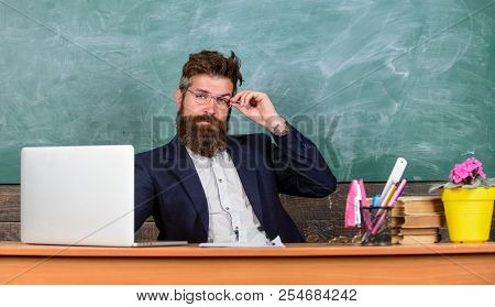 I Am Your New Teacher. Teacher Bearded Hipster With Eyeglasses Sit In Classroom Chalkboard Backgroun