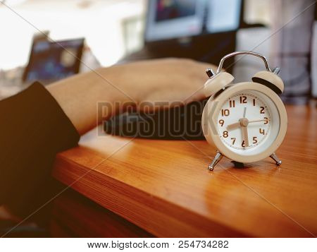 Close Up Small Alarm Clock With Officer Hand On The Laptop To Start Working In Working Hour In The M