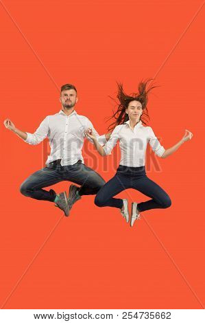 Freedom In Moving. The Happy Young Couple Jumping And Gesturing Against Red Studio Background. Runni