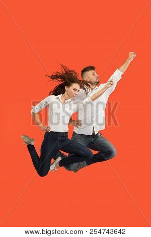 Freedom In Moving And Forward Motion. The Happy Young Couple Jumping And Gesturing Against Red Studi