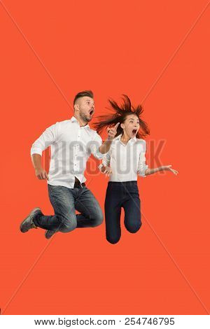 Freedom In Moving And Forward Motion. The Surprised Young Couple Jumping And Gesturing Against Red S
