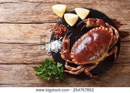 Raw Brown Crab With Lemon, Parsley And Spices On A Slate Board Close-up On A Table. Horizontal Top V