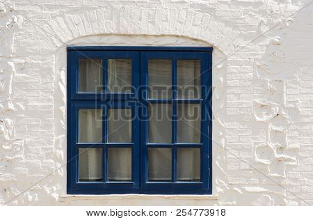 Blue Painted Wooden Window Frame Set In Whitewashed Brick And Stone Wall.