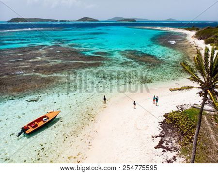 Aerial drone view of Petit Tabac tropical island, turquoise Caribbean sea of Tobago cays, and a family with kids in St Vincent and Grenadines