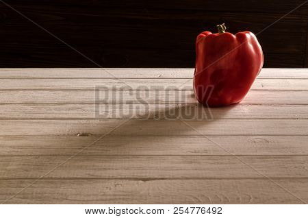 Red Sweet Pepper On A Wooden Table. Bell Pepper Throws A Shadow On The Table. Red Bell Pepper On A D
