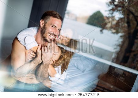 Back View Of Woman In Black Panties Holding Her Bra While Man Is Lying On Bed