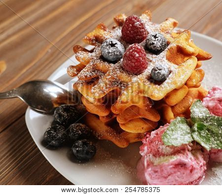 Plate of belgian waffles with ice cream and fresh berries - raspberries and blueberries.top view close-up.