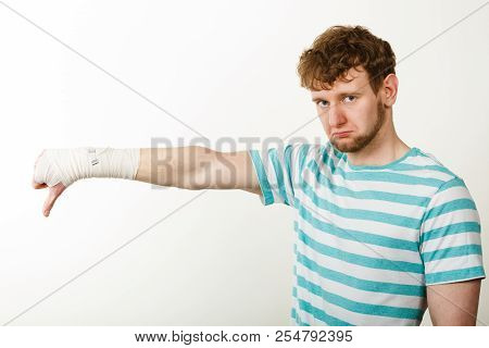 Bad News And Information. Medicine Aspects. Sad Unhappy Male With Bandaged Hand Showing Thumb Down S