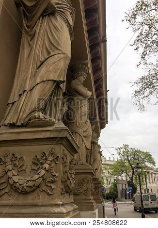 Large Statues On The Streets Of The City, Statues Of People Holding A Building On Their Heads, A Lit