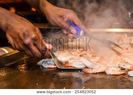 Hands Of A Chef Preparing Shrimp At Table Side Service In Restaurant