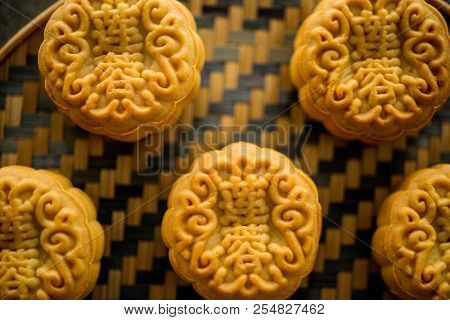 Traditional moon cakes is offered to friends or family during Mid-Autumn Festival. Flatlay on table, top down view dark background. The Chinese character represent 