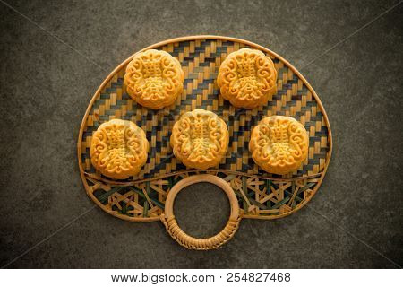 Traditional baked mooncakes is offered to friends or family during Mid-Autumn Festival. Flatlay on table, top down view dark background. The Chinese character represent 