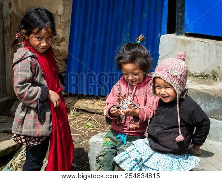 GHALEGAUN, NEPAL - CIRCA MAY 2018: Three young Nepali girls playing outside their home.