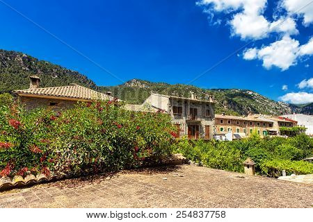 Old Buildings, Blooming Plants And Mountains In Town Valdemossa, Mallorca, Spain