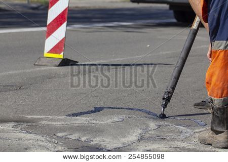 Workers Repair The Road, Pour Small Cracks With Bitumen To Prevent Further Destruction Of The Road S