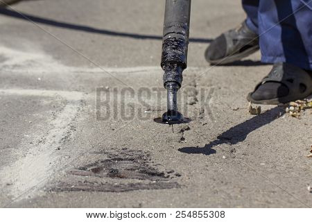 Workers Repair The Road, Pour Small Cracks With Bitumen To Prevent Further Destruction Of The Road S