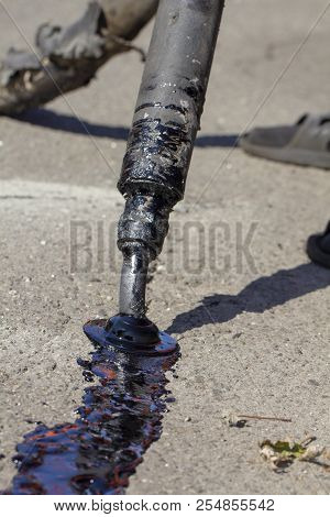 Workers Repair The Road, Pour Small Cracks With Bitumen To Prevent Further Destruction Of The Road S