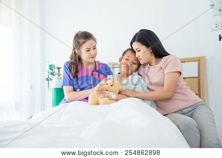 Young Asian Female Doctors Visiting Child Patient On Ward